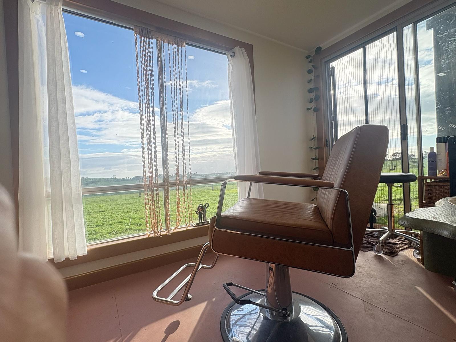 Styling chair beside a large window overlooking green paddocks